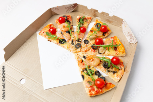 Pizza slices with shrimp, olives, and tomatoes in a box