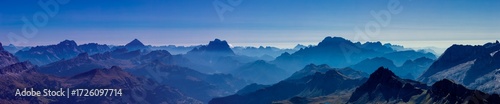 Panorama of Alps mountains on a sunny day. High resolution widescreen panorama of mountain landscape. Blue sky with some clouds above beautiful summits alpine range Dolomite Alps in Italy
