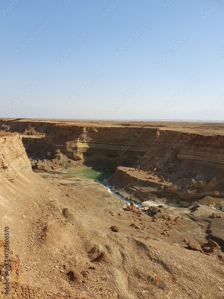 Fototapeta premium Secret river on the dead sea, view of a long and dry salt river stream in the northern part of the dead sea, Jordan Rift Valley, Israel. Stream in layered clefts and faults in muddy salinity unstable