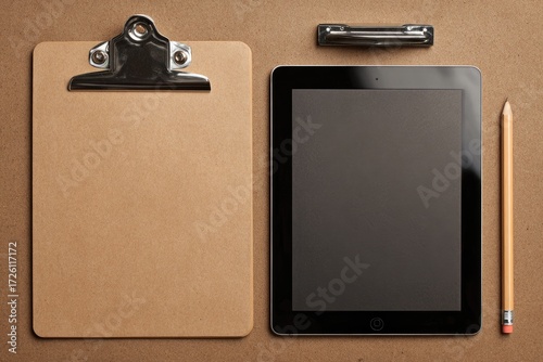 Flat lay of clipboard, tablet, and pencil on kraft paper
