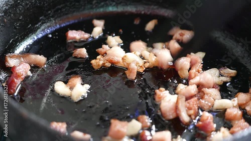 POV: Someone frying bacon in a frying pan. Cooking bacon in a skillet. A person mixing bacon pieces.