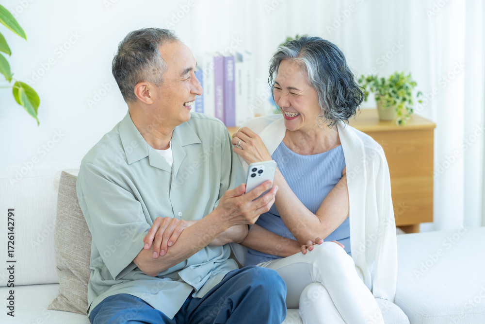 Obraz premium リビングでスマホを見るシニア夫婦