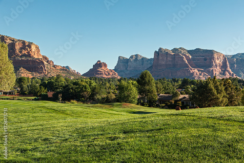 A beautiful landscape of red rock mountains, blue sky, and a golf course in the Village of Oak Creek, Sedona, Arizona, Yavapai County, USA.
