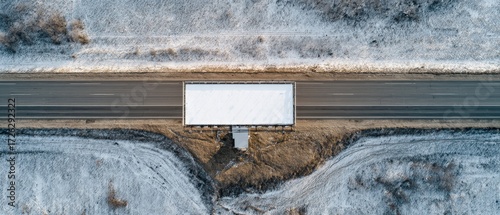 Aerial view of a blank billboard along a desolate winter highway, advertising space.