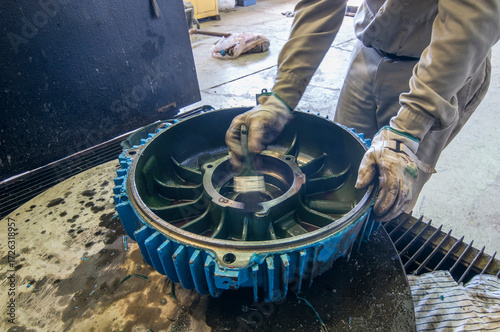 Technical personnel cleaning an electric motor cover as part of preventive maintenance at a geothermal plant workshop in Mexico.