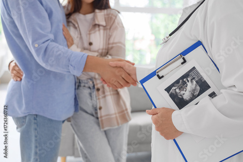 Tableau sur toile Female fertility doctor with couple shaking hands after IVF in clinic, closeup