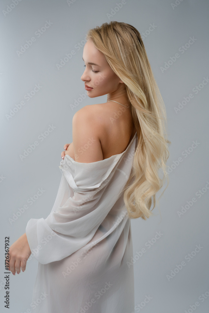 Fototapeta premium Blonde woman poses gracefully in a studio setting with soft lighting