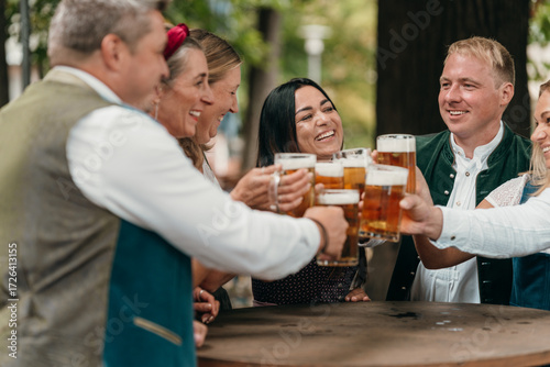 Men and women in Bavaria cheer with beer mugs at beer garden celebrating Oktoberfest friendship leisure German tradition and festive culture