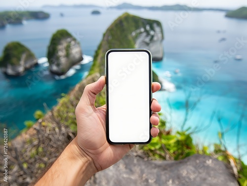 A hand holds a smartphone with a blank white screen against a backdrop of a tropical coastline with islands and turquoise water.