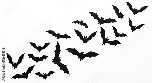 Scattered flock of black bat silhouettes flying in a chaotic pattern isolated on white background with a Halloween theme