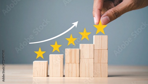 Hand places final yellow star atop ascending block stacks—curved arrow and structured rise evoke achievement, improvement, and rating progression in minimalist success symbolism composition.