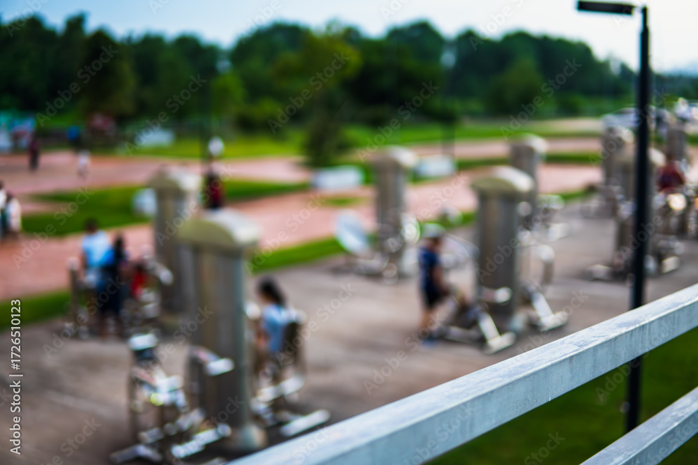 Fototapeta premium Group of people enjoying exercise on a public park bridge with fitness equipment, highlighting health, lifestyle, and background atmosphere in a vibrant outdoor space.