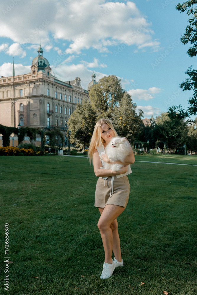 Fototapeta premium Woman with fluffy Pomeranian in city park