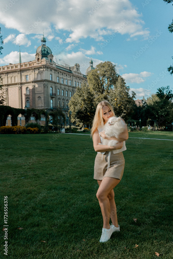 Fototapeta premium Woman holding fluffy Pomeranian in city park