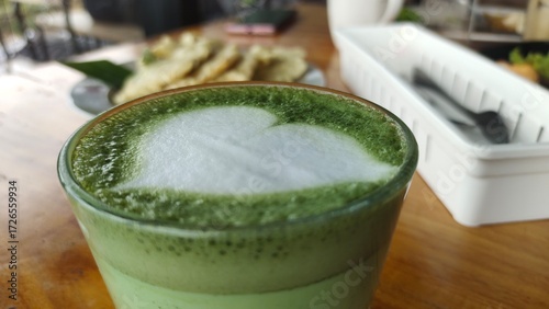 a glass of matcha latte with love latte art green drink sweet