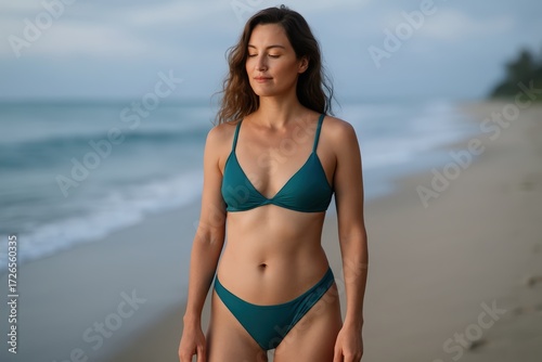 Young Woman Wearing Teal Bikini Standing on Beach in Natural Sunset Light