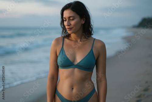 Young Woman Wearing Blue Bikini Standing on Beach with Ocean Background