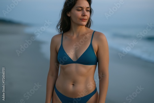 Young Woman Wearing Blue Bikini Standing on Beach During Sunset