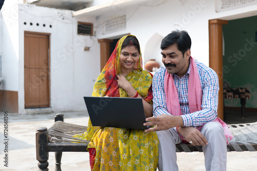 Tableau sur toile Indian happy rural couple using laptop in village at home