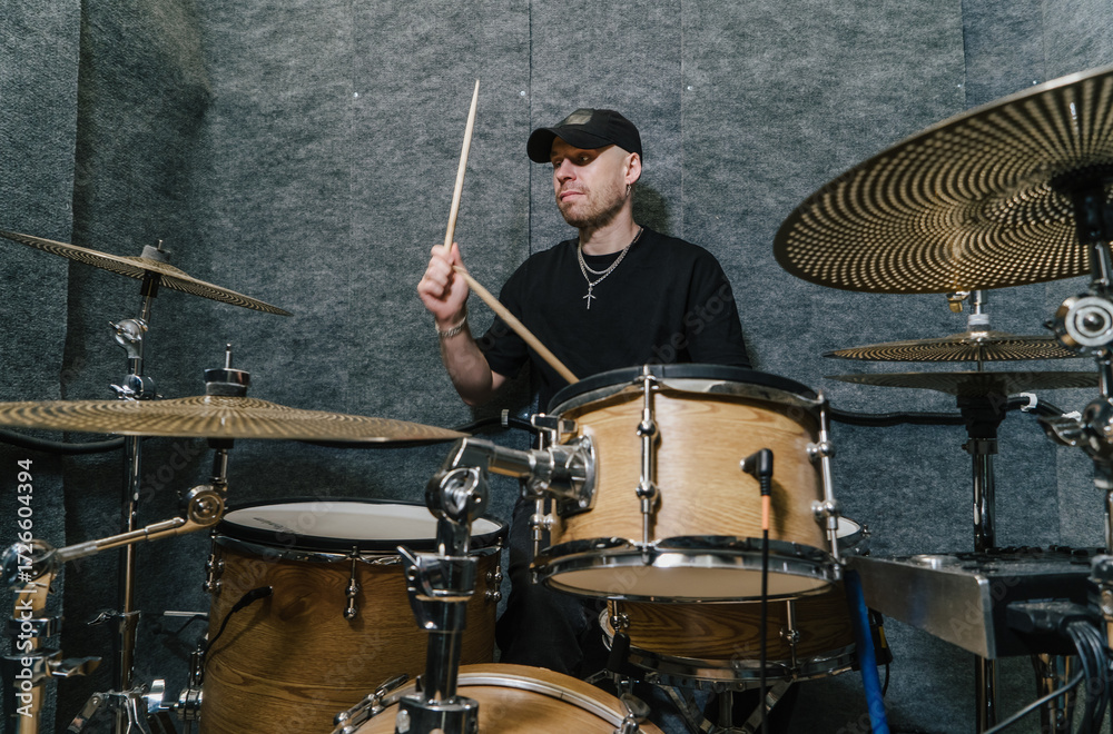 Fototapeta premium Drummer playing drums in soundproof studio room, practicing musical performance, producing rhythmic beats, creating music, working in professional environment, modern music industry concept.