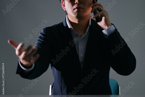 Canvastavla 暗い室内でスマートフォンで通話中に相手と口論になる怒るスーツを着た悪徳業者