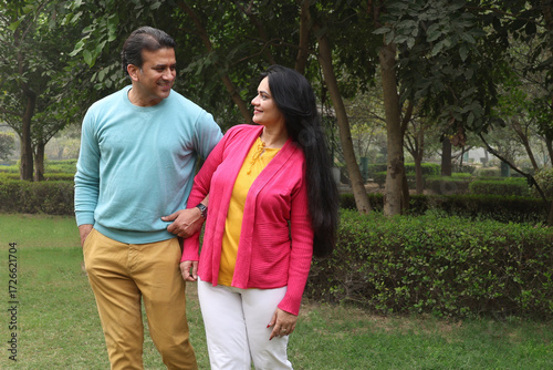 Indian happy young couple standing and looking each other with love and care. Indian Smiling young couple holding hands and standing outdoors at the nature. Celebrate the form of love at park