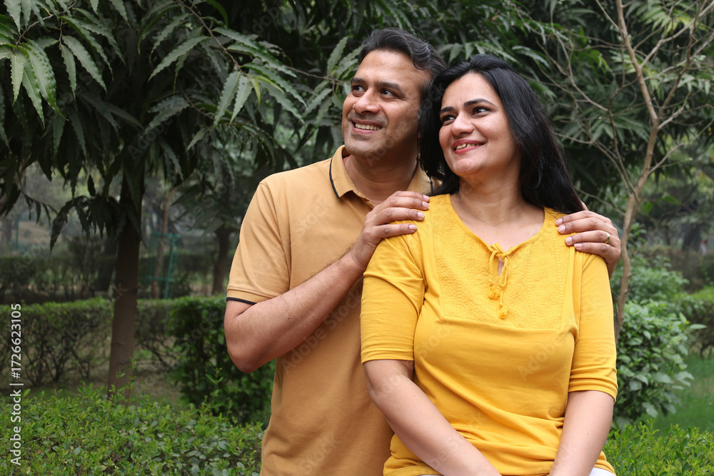 Fototapeta premium Indian young lovely couple hugging outdoors at the nature. Portrait of happy young indian couple fun together, husband wife morning walk outdoor. enjoying summer day outdoors.