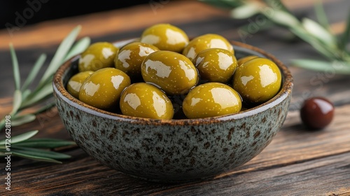 Green olives in a bowl on a wooden table