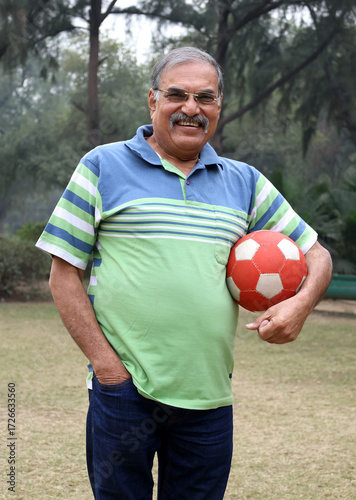 Indian old man holding a football at park