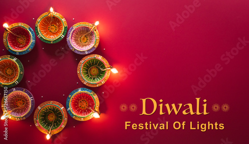 Happy Diwali - Clay Diya lamps lit during Diwali, Hindu festival of lights celebration. Colorful traditional oil lamp diya on red background