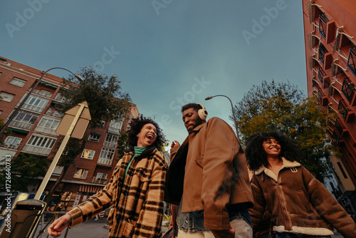 Group of young friends walking down the street laughing and having fun