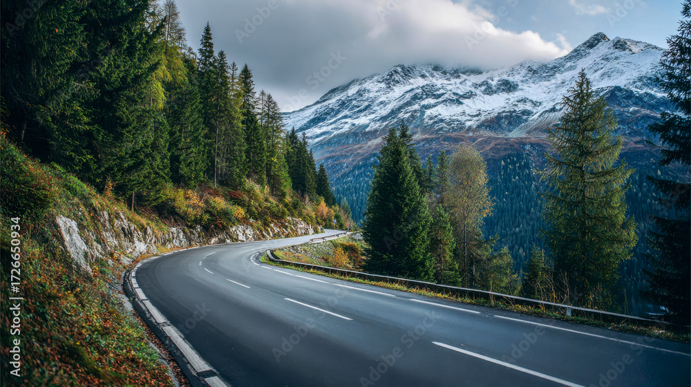 Fototapeta premium Winding road through lush green hills and majestic mountains during a calm daytime scene