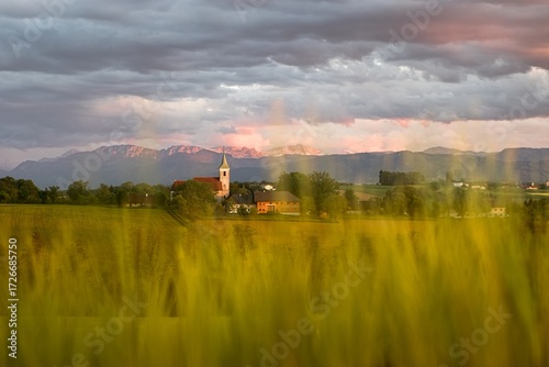 Village church with fields and mountains at sunset in Upper Austria