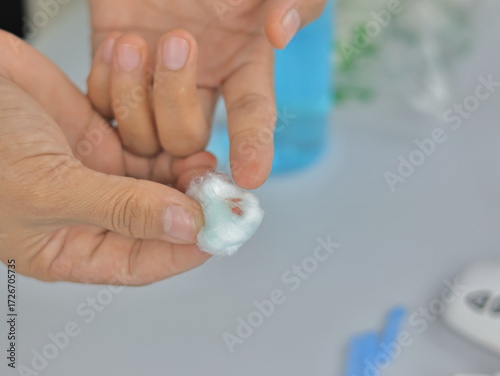 Tableau sur toile A close-up shot of a hand holding a cotton ball with a small amount of blood, likely from a minor injury or a blood test