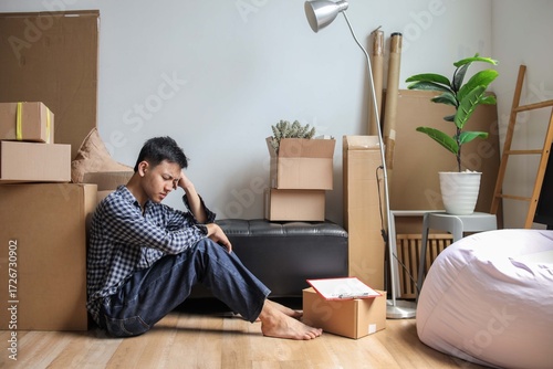 Frustrated Man Sitting on Floor with Head in His Hands Surrounded by Moving Boxes
