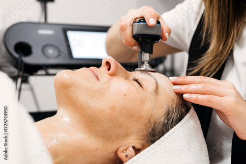 Bilde på lerret Female patient receiving RF lifting treatment for facial rejuvenation in a moder