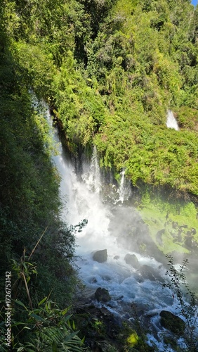 Beautiful Saltos Ojos del Huishue waterfall in southern Chile, surrounded by lush green forest and rugged rocks, a stunning natural escape.