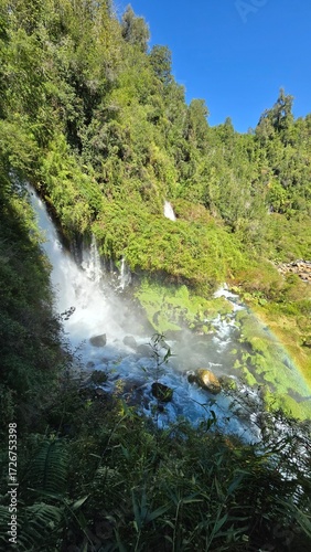 Beautiful Saltos Ojos del Huishue waterfall in southern Chile, surrounded by lush green forest and rugged rocks, a stunning natural escape.