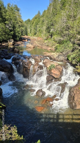 A breathtaking waterfall cascading through lush greenery, surrounded by forest and rocks, capturing the beauty and power of untouched nature.