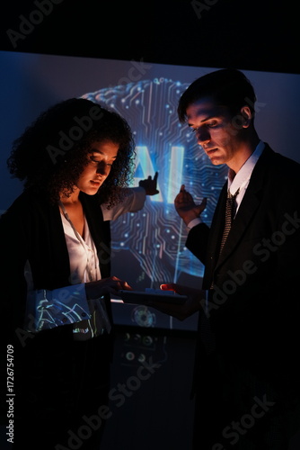 female IT development staff member and a male colleague stand in front of a conference room explaining how to use a data management system, business intelligence, data statistics, and marketing analys