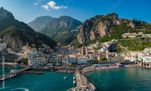 Aerial view of sun-kissed buildings tumbling down to the vibrant turquoise sea, nestled amidst rugged mountains, Amalfi, Almalfi Coast, Campania, Italy.