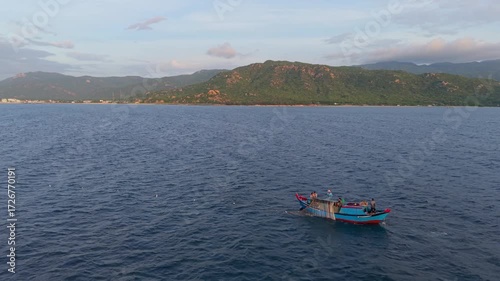 Aerial view of fishing boat on ocean, fishermen working with nets, traditional livelihood and authentic lifestyle of coastal Vietnam. Fishermen pulling nets on wooden fishing boat at sea 