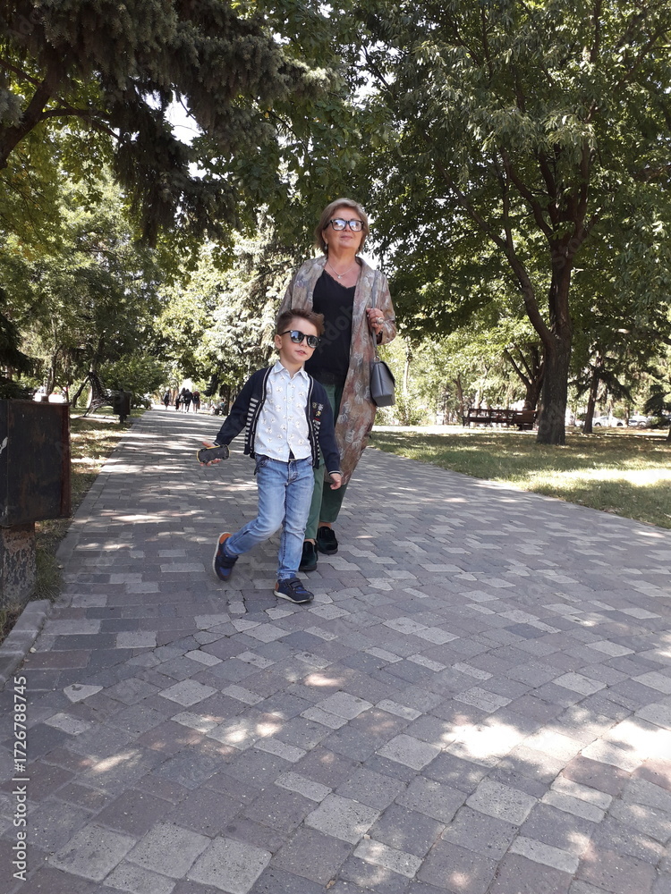 Fototapeta premium Caucasian elderly female and young child walking in park with trees