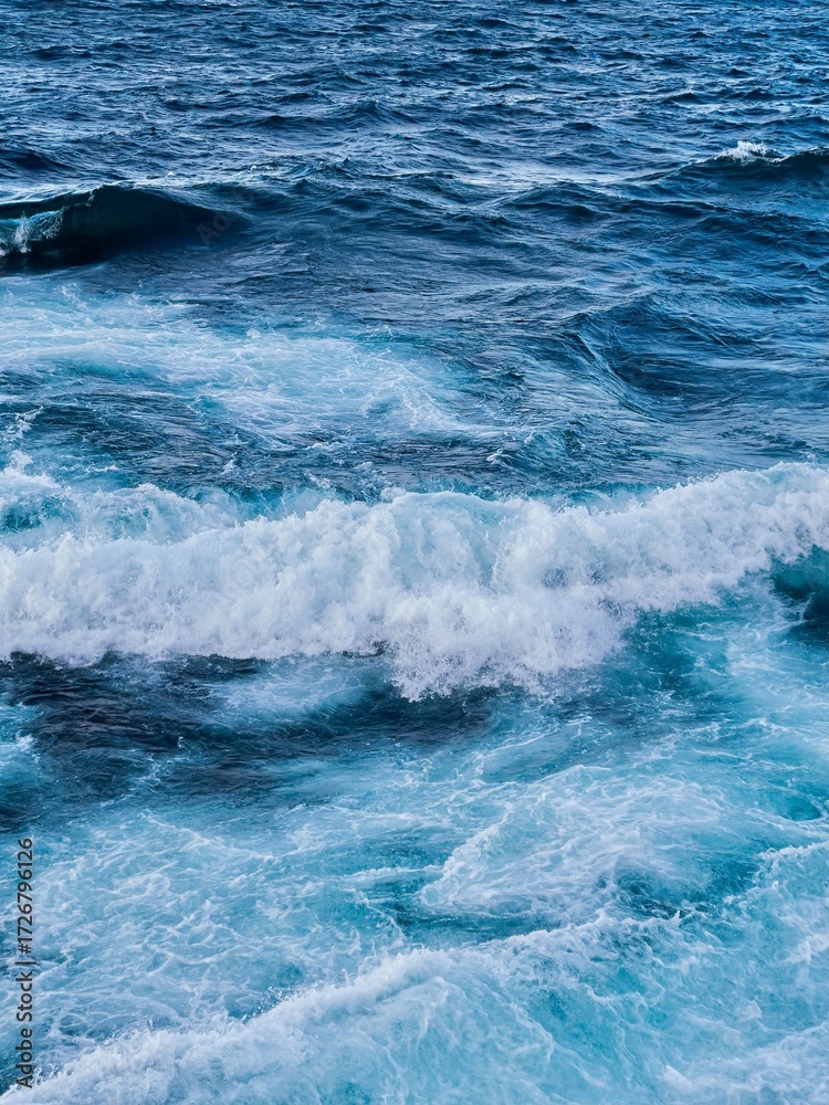 Fototapeta premium Aerial view of ocean waves, boats and sunset
