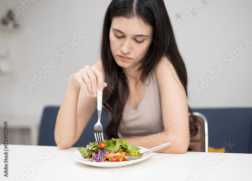 A young woman with no appetite eats a boring and unpalatable breakfast.