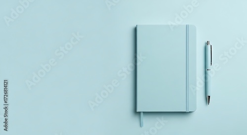 Minimalist flat lay of a soft green notebook and pen on a green background