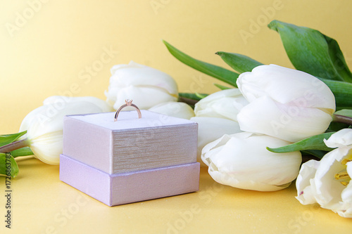 white tulips and engagement ring in a case on a light background