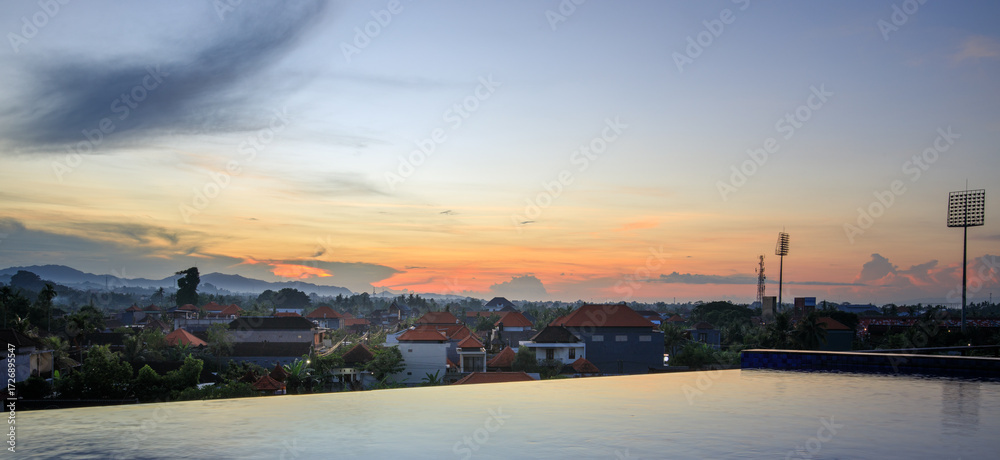 Obraz premium Beautiful sunset over a city with a pool in the middle