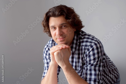 Portrait of caucasian curly friendly bearded man looking at camera smiling leaning on hands. Positive brunet white male feeling joy, optimism. Joyful relaxed guy enjoying life. Sincere human emotions.
