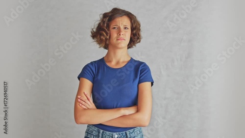 Doubtful young girl raising eyebrow with crossed arms showing skepticism and critical assessment. Ideal for doubt and critical assessment content